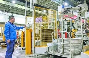 圖：工作人員在5G全連接工廠的成型區(qū)內(nèi)操作機械手